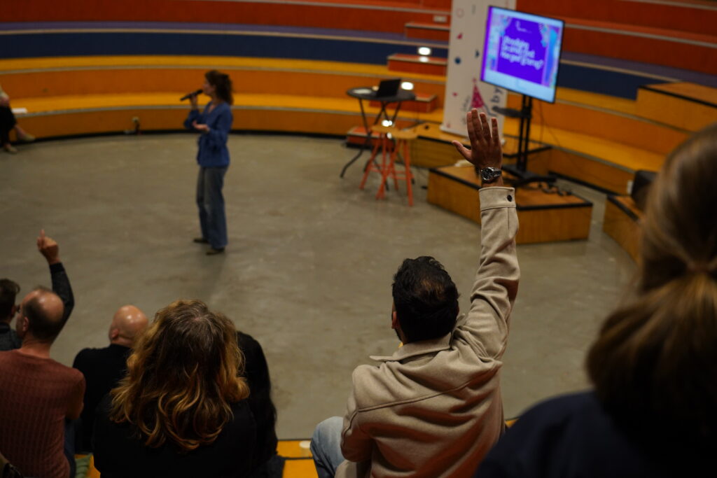 Bezoeker steekt zijn hand op tijdens de plenaire sessie
